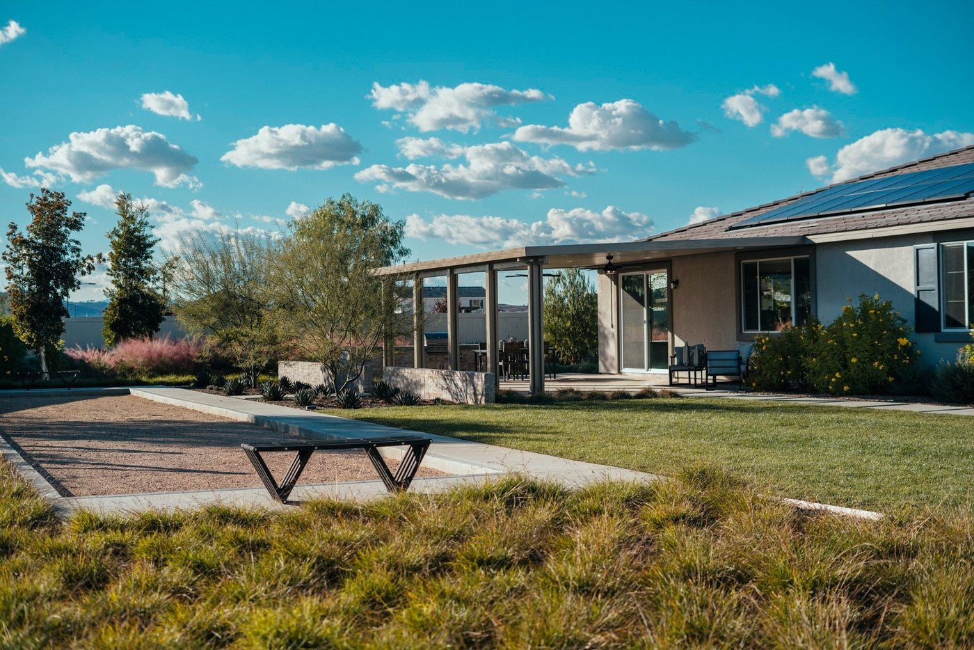 home with solar panels and an attached patio cover under a beautiful afternoon sky