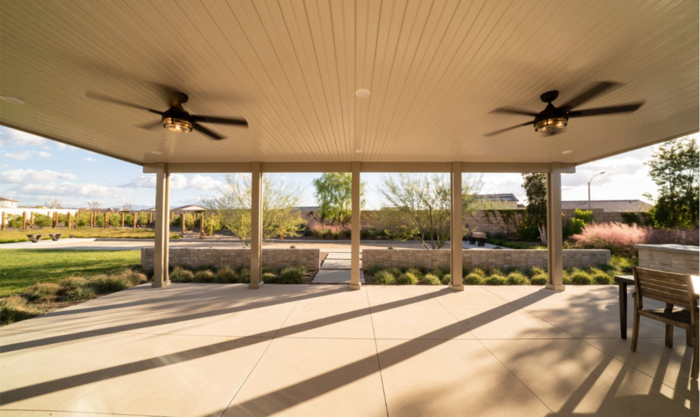 Large patio cover attached to house with four posts and two ceiling fans