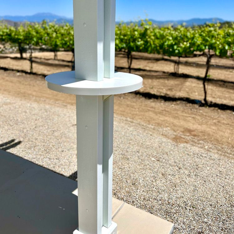 White alumatable shown installed on a white patio cover post next to a vineyard