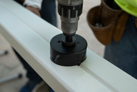 Contractor drilling a hole into an alumawood patio cover post using a special drill